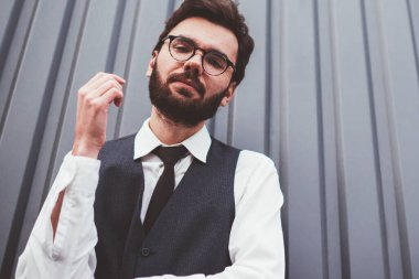 Beyaz tenli yakışıklı adamın portresi. Gri promosyon arka planının yakınındaki kameraya bakıyor. Gözlüklü genç bir öğrenci.