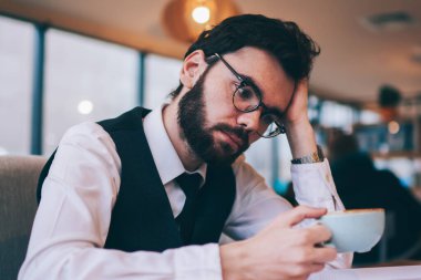 Kafeteryada elinde kafein bardağıyla roman tutan düşünceli bir adam, kahve molası sırasında ders kitaplarından kitap okuyan düşünceli hippi adam.