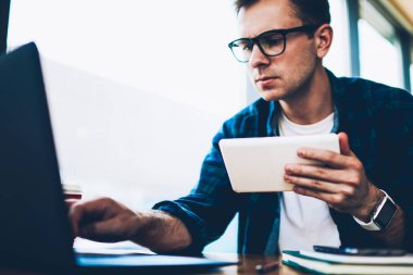 Genç yakışıklı dalgın yetenekli freelancer şık Eyewear dizüstü bilgisayar online bankacılık hizmeti üzerinden para transferi. Düşünceli erkek öğrenci bilgi kapalı ağ arama