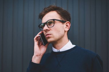 Genç yakışıklı adam havalı gözlükler Sokağı'nda cep telefonu uygulaması aracılığıyla mobil konuşmayı görüntüsünü kapatın. İyi görünümlü erkek kişi cep telefonu açık havada durmuş ise konuşuyorum