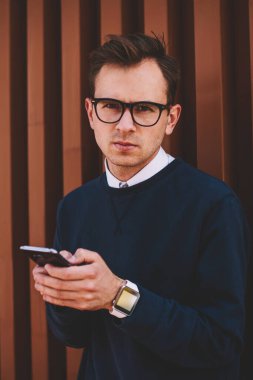 Yarım uzunluk portre serin gözlük ile sokulgan yolu ile smartphone ve 4 g olarak sosyal ağlar sohbet kendine güvenen insanın. Yakışıklı hipster adam telefonla e-posta iletisi gönderirken kameraya bakıyor