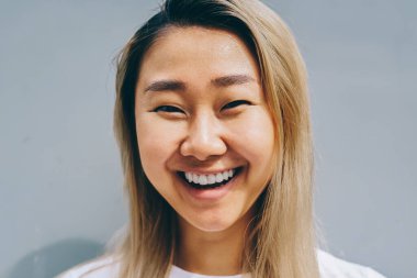 Üzerinde mavi arka plan, neşeli sarışın Asyalı kadın gömlek markası veya kameraya bakarak etiket için kopya alanı ile poz gülüyor serbest zaman sırasında eğlenmek şirin Asyalı kız portresi yarım uzunluk