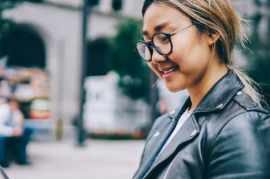 Gülümseyen Asya kız öğrencinin banka şehir okuma e-kitap, ağlar ve paylaşım Multimedya açık havada sohbet için tablet üzerinde uygulama kullanarak Eyewear olumlu Çinli kız dinlenme