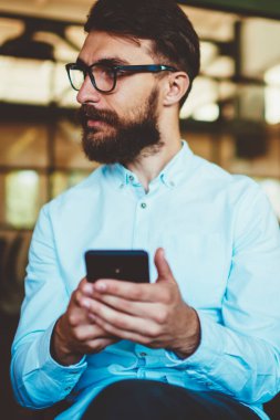 Düşünceli sakallı hippi adam cep telefonuyla işten gelen e-postayı inceliyor. Gözlüklü genç yakışıklı adam görüşünü düzeltmek için iletişim ve mesajlaşma teknolojisini kullanıyor.