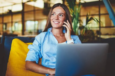 Dost canlısı akıllı telefon konuşmaları sırasında dizüstü bilgisayarda bilgi arayan neşeli yirmili yaşlardaki kız öğrenci, mutlu başarılı kadın kapalı alandaki telefon konuşmalarıyla olumlu haberler aldı.