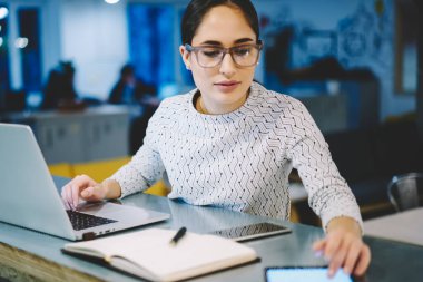 Modern teknolojiler, iş kadını ofiste oturmuş boş tablet monitör gelir mesaj okuma kullanarak masaüstü çalışan touchpad üzerinde uygulama yükleme Eyewear yetenekli kadın Tasarımcısı