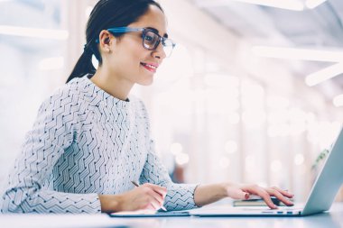 Dizüstü bilgisayar, netbook, online tablete imzalama belgelerin incelenmesi pozitif kadın Yöneticisi ile tasarımı skeçler tablete oluşturma teknolojisini kullanarak ofisinde çalışan gülümseyen kadın bağlı