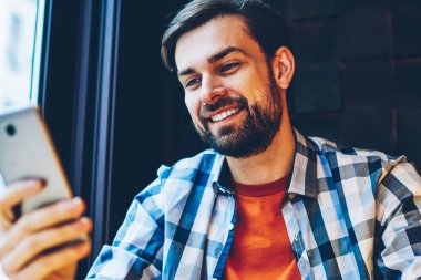 Başarılı sakallı modern smartphone cep telefonu ile 4 g üzerinden online sohbet mesajlaşma delikanlı uzay coworking oturan internet. Pozitif hipster blogger ile hücresel cihaz üzerinde iyi haber bildirim okuma