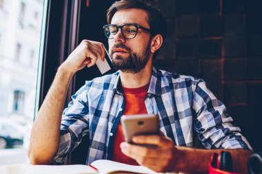 Kartvizit smartphone ile kafede oturan çalışma önerisi üzerine düşünme elinde düşünceli sakallı hippi herif. 4 g üzerinden para işlem üzerinde durulması dalgın genç adam cep internet