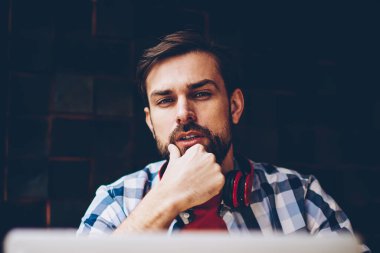 Serbest üzerinde çalışma ve dizüstü bilgisayarda kablosuz 4 g internet bağlantısı kullanarak yakışıklı sakallı hippi adam portresi. Netbook okurken kameraya bakarak boyun kulaklık ile genç adam