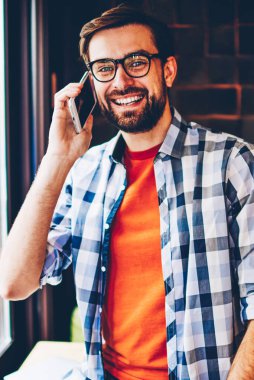 Mutlu sakallı genç adam portresi smartphone telefon görüşmesi sırasında ilgili komik Haberler arkadaşıyla konuşurken kameraya gülümseyen trendy forması giymiş. Neşeli hipster adam cep üzerinde iletişim
