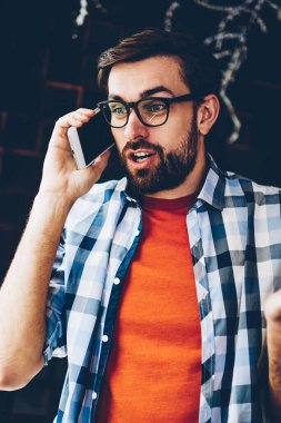 Sakallı genç adam şaşırmış arkadaşı ile telefon görüşmesi sırasında dijital smartphone aygıt üzerinde konuşuyor haberleri ile hayran. Hipster adam heyecan şok hikaye modern telefonla arama ile merak ettim