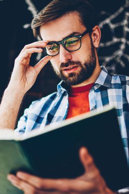 Sakal ve optik gözlük yararlı bilgiler ders için ders kitabı arama akıllı genç adamla yoğunlaşmıştır. Dalgın hipster adam okuma kitabı coworking seminerde okuyan için hazırlanıyor