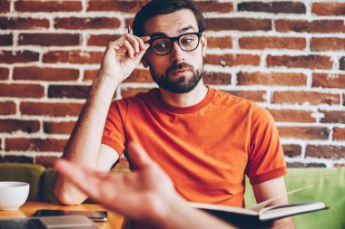 Planları ve coworking ortak başlangıç projesi geliştirmek için fikirleri tartışılması sırasında meslektaşım vizyon düzeltme uzakta iken dikkatle bakmak için şık gözlük hayran genç adam dinleme