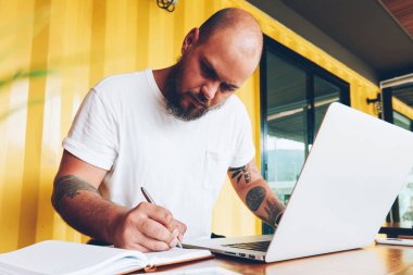 Ciddi bin yıllık erkek öğrenci dizüstü bilgisayar ve wifi college Kampüsü, notlar üzerinde serbest çalışma makale yayın için yetenekli erkek blogger kullanarak ödev Not Defteri'nde yazma