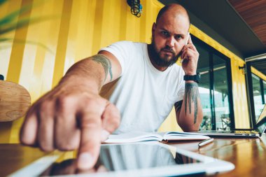 Başlangıç yazılım güncelleştirmesi için dijital tablet telefon ve basın güvenlik kodu konuşurken ciddi sakallı adam portresi, bin yıllık adam akıllı telefon konuşmayı unlock için ekrandaki parmak koymak