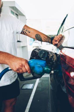 Petrol ve petrol istasyonu, Genç adam benzen Servisi, çevre kirliliği kavramı üzerinde hortum ile otomobil tank pompa ile araç araba şarj meme tutan erkek kırpılmış görüntü