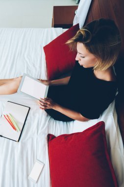 Kadın blogcunun portatif bilgisayarını elinde boş ekranla yatakta dinlenirken üst görüntüsü, web mağazasında broesing web sitesinde alışveriş yapan genç bir kadın, rahat ev içi ilişkilerde zaman harcayan bir tablet.