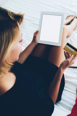 Taşınabilir bilgisayarla para kazanan bir kadının evdeki rahat yatağında oturması, hister kızın internet mağazasında dijital tablet kullanarak alışveriş yapması ve internet bankacılığı yapması.