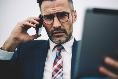 Kendine güvenen orta yarım uzunluk portre smartphone aygıtında çağrılırken kameraya bakarak girişimci yaşlı. Ciddi icra müdürü 50 yaşında elinde cep telefonu üzerinde konuşurken dokunmatik yüzey ile