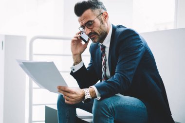 Zengin işadamı metin belgelerinin smartphone aygıt üzerindeki banka hesabınızı kontrol etmek için arıyor operatör için ise orta yaşlı okuma finansal raporlarında. Başarılı gurur CEO'su cep üzerinde konuşuyor