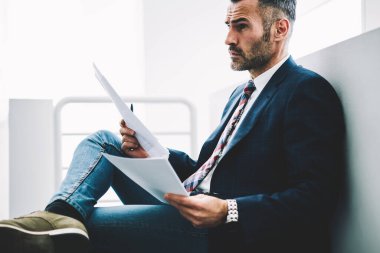 Girişimci 50 yaşındaki formal giyim ofis iç oturan kağıt mali belgelerin incelenmesi eski durulması. Muhasebe raporları holding ve düz seyir düşünceli olgun tüccar