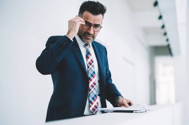 Orta yaşlı işadamı yarım uzunluk portre formal giyim ayakta finans şirketi office Ardiles belgelerle giyinmiş. Kameraya bakarak formal giyim başarılı olgun girişimci