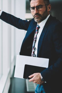 Kendine güvenen başarılı işadamı modern tablet aygıtı elinde tutan ve kameraya bakarak 50 yaşında yarım uzunluk portre. Finans şirketinin ciddi olgun sahibi formal giyim giyinmiş