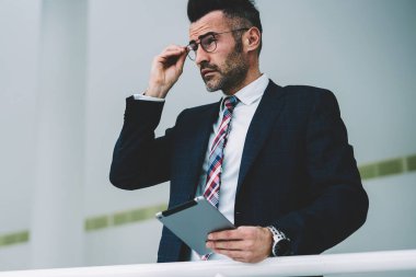 Elinde düşünceli emin girişimci 50 yaşında holding dijital tablet. Formal giyim düşünme modern Dokunmatik ped cihaz üzerinde alınan bildirim üzerinde durulması olgun işadamı giymiş