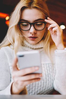 Kafedeki akıllı telefon uygulaması aracılığıyla bankacılık bakiyesini kontrol eden düşünceli genç bir kadın, telefondaki faturayla ilgili konsantre kadın okuma bildirimi işlem yapmak için internet uygulaması kullanıyor