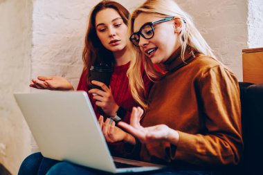 Dizüstü bilgisayarda yer ayırtırken tartışan genç kadınlar bakış açılarını paylaşıyorlar, genç bayan öğrenciler problem iletişimini çözüyor ve proje fikirlerini açıklıyorlar.