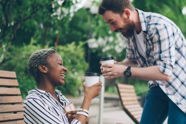Çok ırklı mutlu çiftin, kahve içip tezahürat yapmasının ve yaz kenti parkında vakit geçirirken şaka yapmalarının yan görüntüsü.
