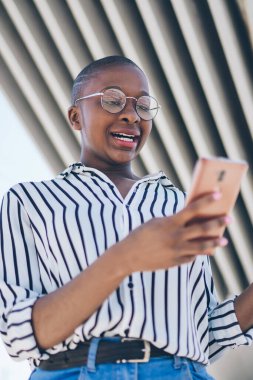 Akıllı telefondan mesaj okuyan ve şehir köprüsünün altında dururken el sallayan kafası karışmış genç Afro-Amerikan kadınlarından.