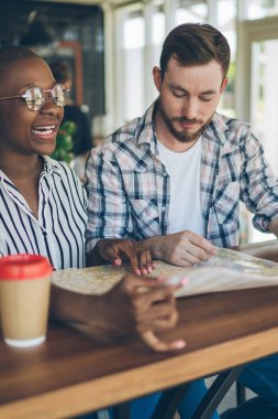Kafe 'de boş zaman geçirirken yeni tatil yeri hakkında konuşurken birlikte harita rehberliği yapan hevesli çift.