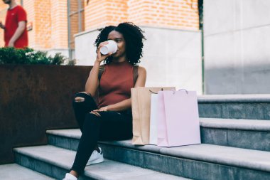 Siyah, güler yüzlü, kağıt torbalarla gezen, yazın granit merdivenlerde kahve içen bir kadın.