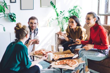 Gündelik kıyafetlerle insanları şaşkına çeviriyor. Bir yandan da pizza kutuları ve yemek fincanlarıyla kanepede oturmuş konuşan kadınları dinliyorlar.