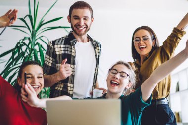 Memnuniyet duyan bir grup sınıf arkadaşı ev ödevlerini tamamladıktan sonra evde çalışırken dizüstü bilgisayara bakıp gülümsüyor.