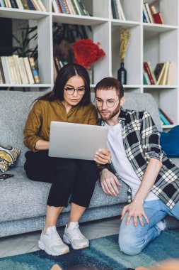 Düşünceli yetişkin insanlar günlük kıyafetleriyle ekrana odaklanıyor ve otururken ve bilgisayar ile iletişim kurarken konuşuyorlar.