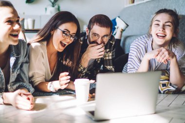 Hafta sonları rahat tasarım odasında yerde uzanan aletlerle evde dinlenen gülen samimi öğrenciler.