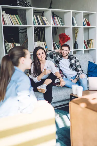 Modern oturma odasında dizüstü bilgisayarla iş yaptıktan sonra sohbet etmek için gelen sıradan bir grup arkadaşı.