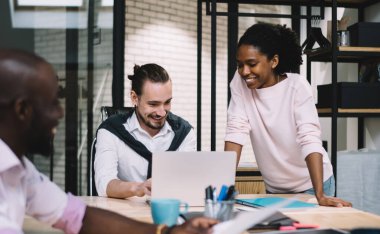 Çok ırklı genç, giyinip kuşanmış iş arkadaşları gündüz vakti şirket toplantılarında gülümseyip fikirlerini paylaşıyorlar.