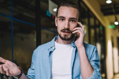 Hayal kırıklığına uğramış, sıradan kıyafetler içinde modern bir erkek cep telefonundan kötü haberler alıyor ve bina koridorunda dikilip kameraya bakarken ellerini açıyor.