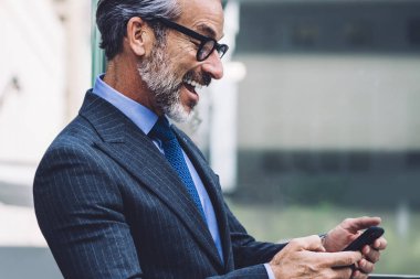 Ofisteki mutlu, olgun iş adamının yan görünüşü. New York 'ta balkonda cep telefonu ve gözlük takması.