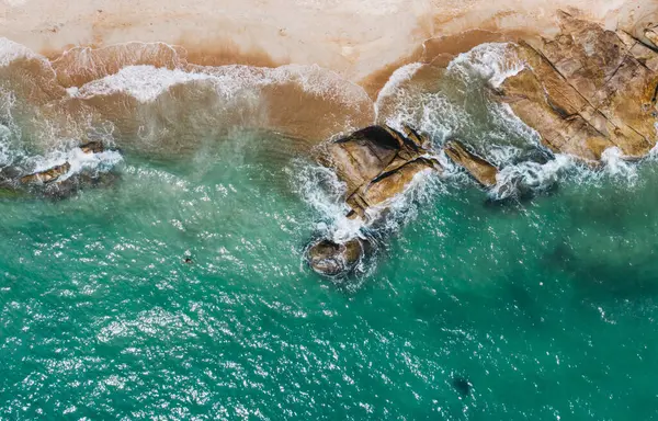 Açık yüzme havuzu ve güneş pansiyonları olan deniz manzaralı otel oteli. Yaz tatilinin kuş bakışı manzarası, turkuaz deniz suyu ve temiz kum kıyısındaki şemsiyeler