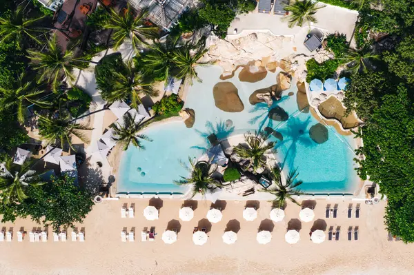 Açık yüzme havuzu ve güneş pansiyonları olan deniz manzaralı otel oteli. Yaz tatilinin kuş bakışı manzarası, temiz kumsalda şemsiyeler.