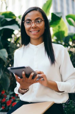 Başarılı koyu tenli kadın ofis çalışanı dijital dokunmatik ped cihaz üzerinde online ödeme yapmadan Eyewear portresi bağlı 4 g için Internet. Tablet ile müreffeh Afrikalı-Amerikalı genç kadın