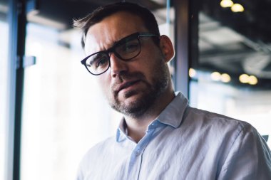 Optik gözlüklü şaşkın erkek girişimcinin yarım boy portresi cep telefonu sorununu çözmek için kameraya bakarken göz koruması sağlar.