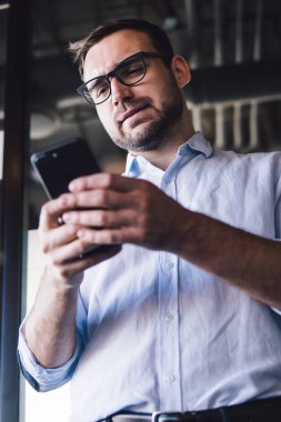 Kafası karışmış iş analizcisi, mobil sohbet için 4G 'ye bağlanan şirket müşterisinden dijital pazarlama sırasında finans haberleri okuyan optik gözlüklü beyaz bir adam mesajı aldı.