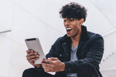 Şaşırmış hipster adam şehir merdivenlerinde dinleniyor haberleri okuyor ve dijital tabletle aldığı e-postaya şaşırıyor kablosuz internete bağlanıyor, modern dokunmatik ped ile mutlu adam ağları ile sohbet ediyor.