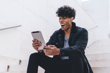 Şaşırmış hipster adam şehir merdivenlerinde dinleniyor haberleri okuyor ve dijital tabletle aldığı e-postaya şaşırıyor kablosuz internete bağlanıyor, modern dokunmatik ped ile mutlu adam ağları ile sohbet ediyor.